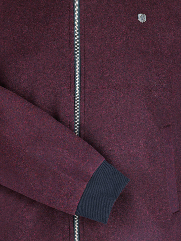 Close-up of silver zipper and metal chest logo on burgundy jacke