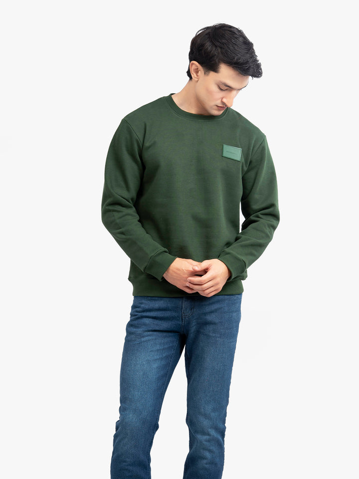 Model wearing dark green crew neck in Pakistan