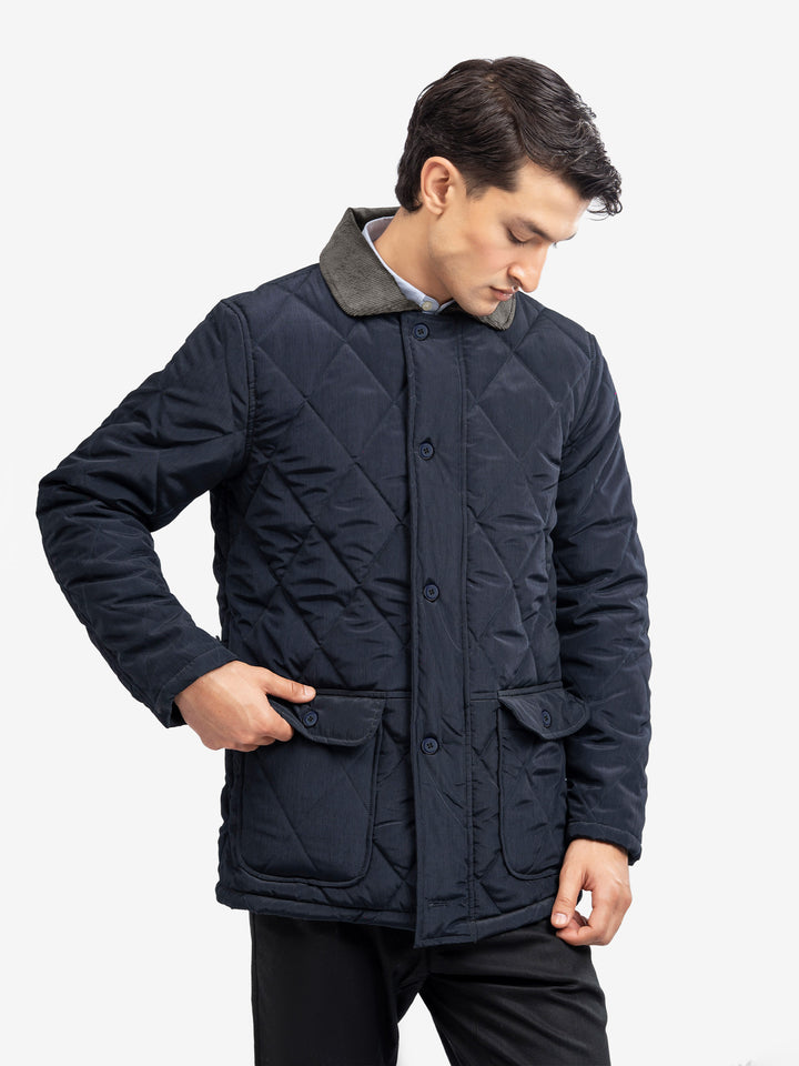 Man wearing navy quilted jacket with corduroy detail
